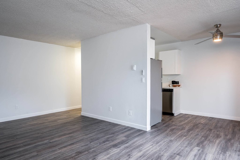 a living room and kitchen with white walls and wood floors